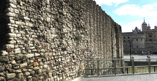 a wall of bricks and stones in london with the tower of london in the background in a clear sky day